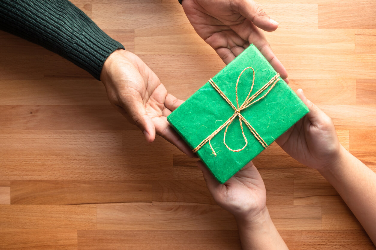 hands exchanging a green wrapped gift