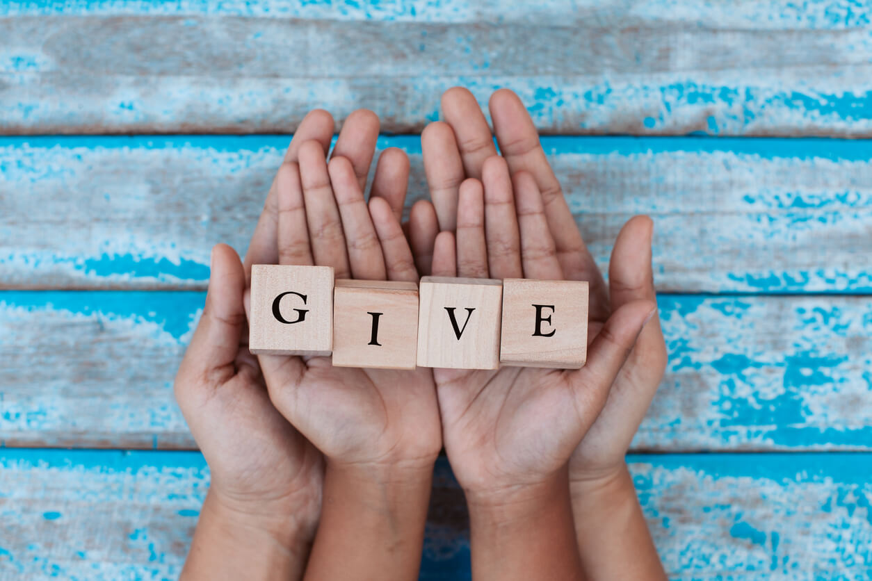 Hands holding blocks that spell the word 'give'